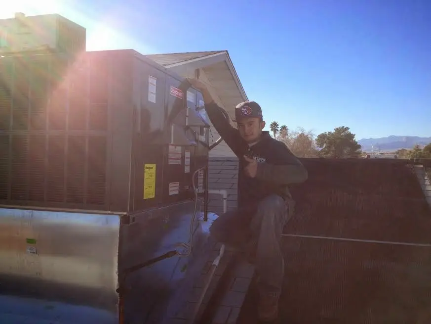 HVAC technician performing AC Tune-Up on a rooftop unit in Alton